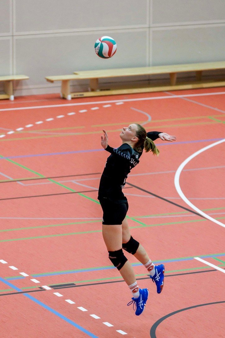 Stephi Bünemann wirft in einer Sporthalle den Volleyball zum Sprungaufschlag hoch